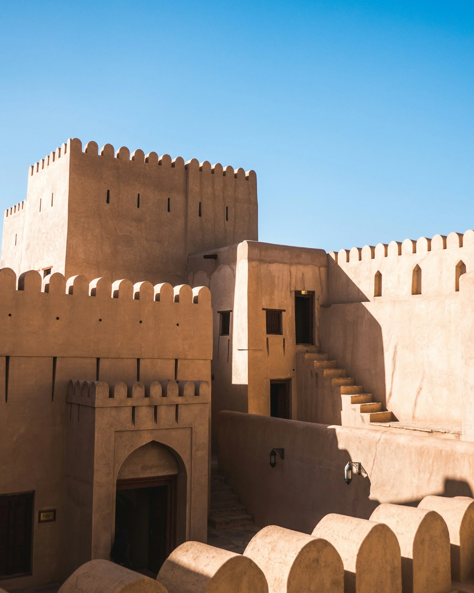 A sandstone fortress with crenellated walls against a blue sky