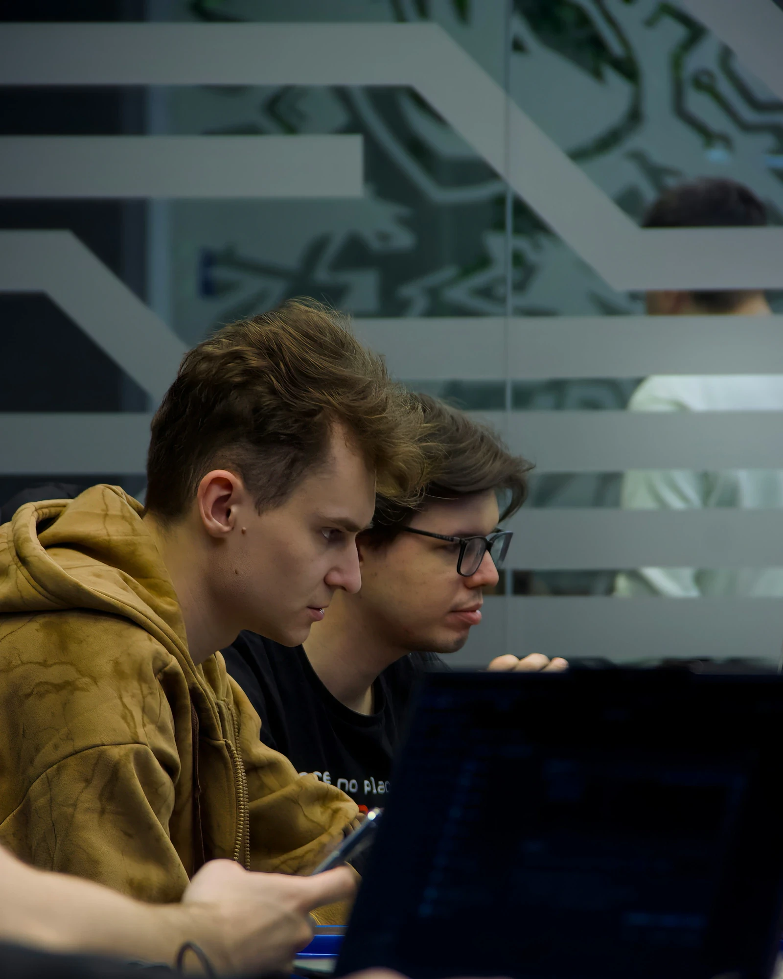 Two security researchers focused on their phones in front of a server room