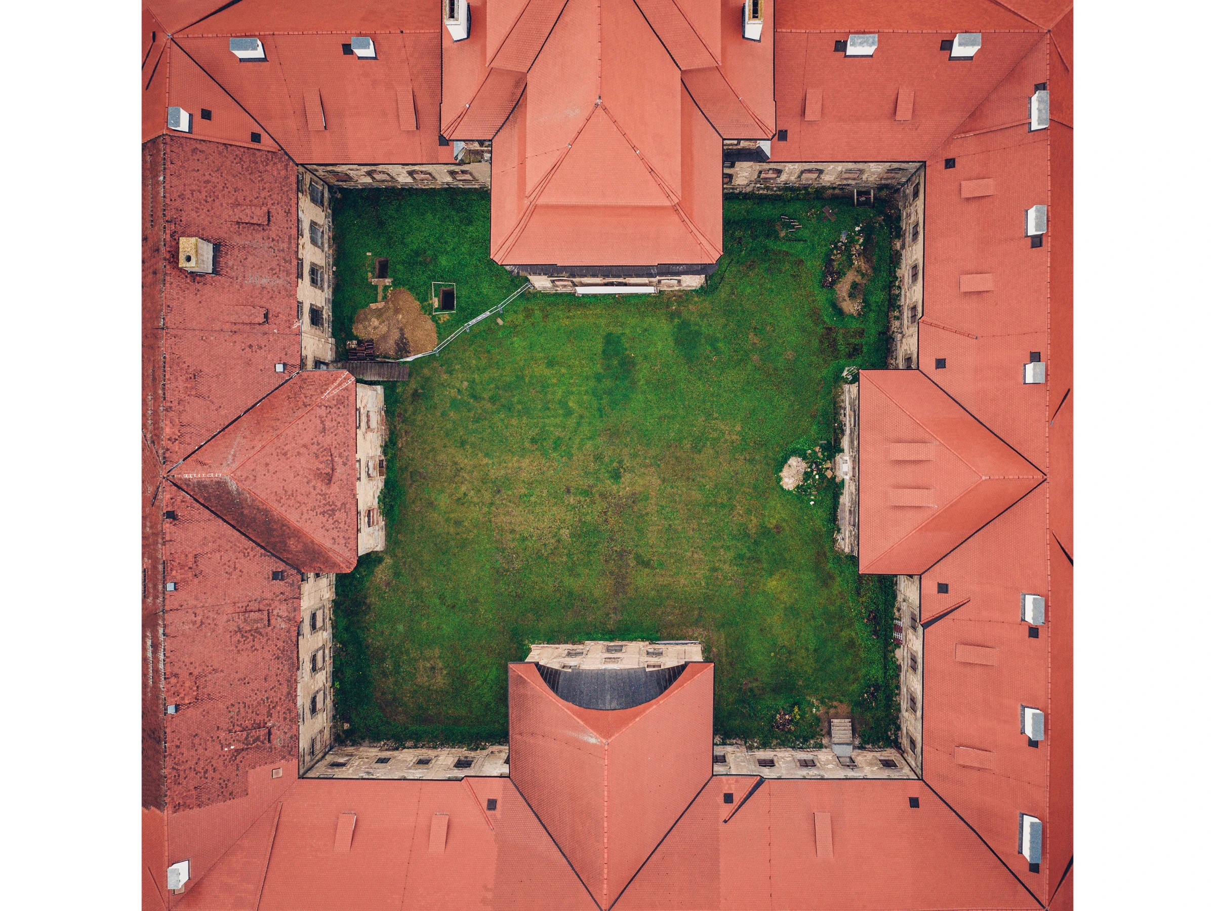 Aerial view of a square courtyard enclosed by red-tiled fortress walls