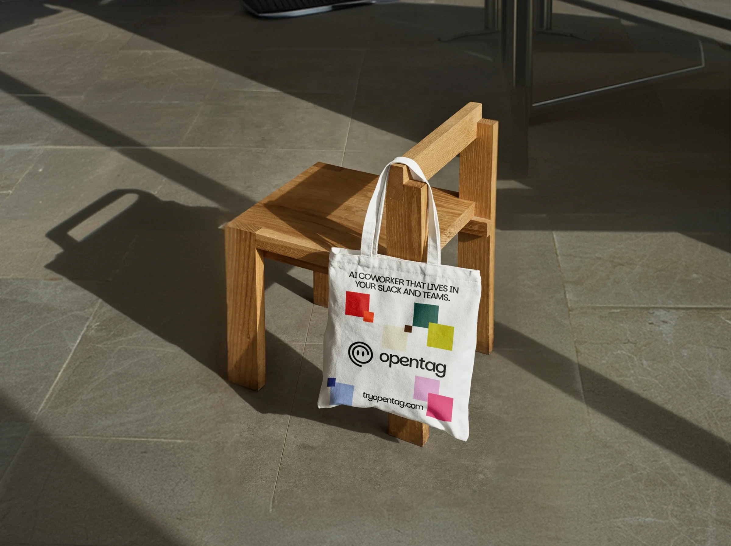 An Opentag tote bag hanging on a wooden chair in sunlight
