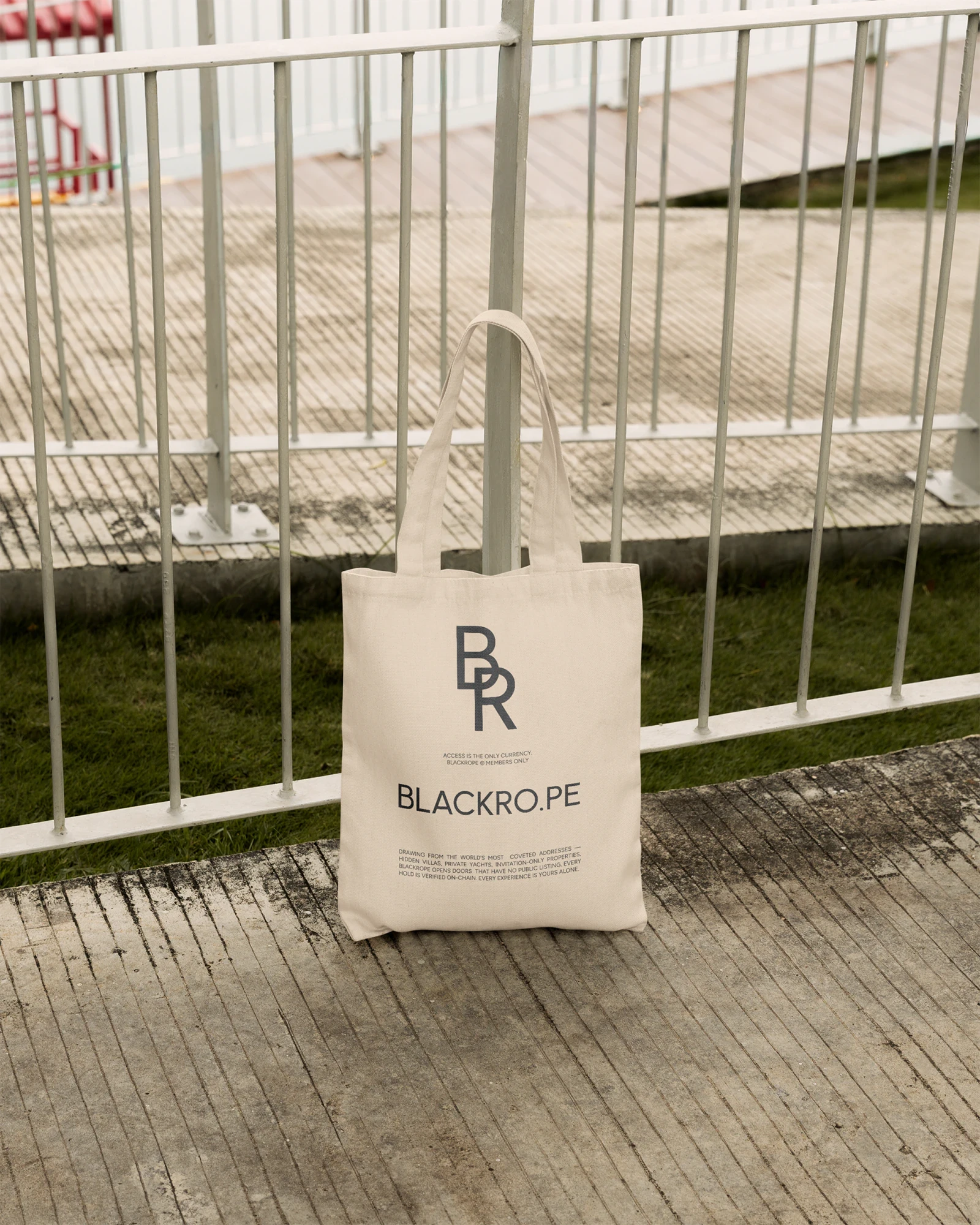 A canvas tote with the geometric monogram resting against a railing