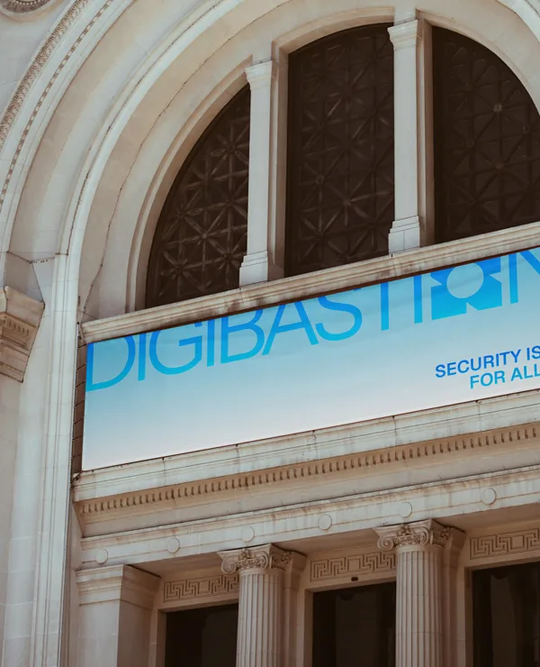A Digibastion banner strung across an arched neoclassical facade, reading “security is for all”
